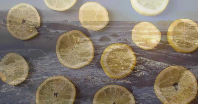 Lemon slices on rocky ocean shoreline with sunset animation in background
