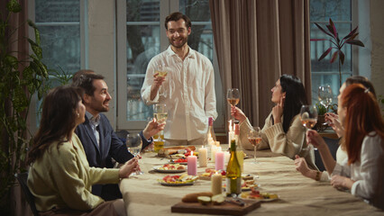 Man standing making toast during group dinner. Concept of leadership moment, celebration speech,...