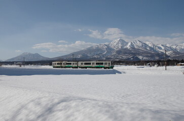 雪の妙高山・黒姫山をバックに走る列車