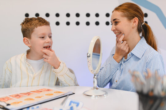 Boy learning speech with therapist using mirror