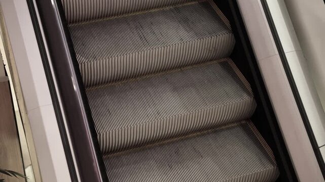 Detailed view of an empty escalator with metal steps and yellow safety lines, captured in a modern indoor setting. No people present