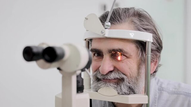 Senior man receiving an eye examination with slit lamp machine, checking eyesight and vision health at an optometry clinic