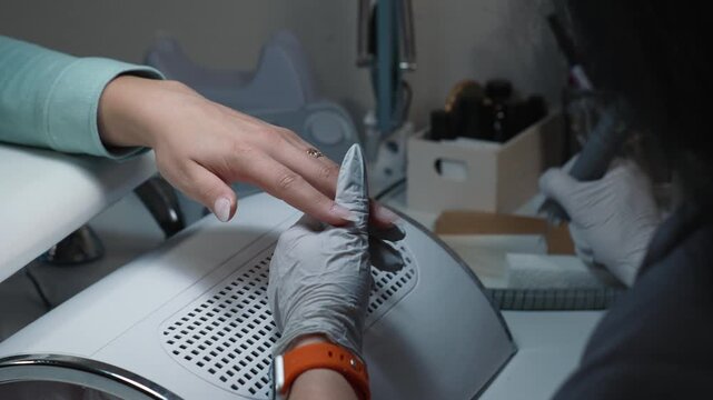 Cuticle and tip border treatment with electric nail drill during acrylic nail modeling in beauty salon
