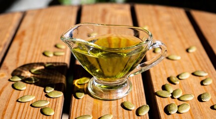 Flat lay composition with pumpkin seed oil in glass pitcher on wooden table. 