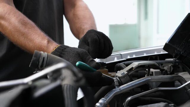 Arms of professional mechanic repairing air conditioner of auto at workplace. Male hands of repairer working under hood of vehicle outdoor. Concept of maintenance and automobile diagnostic. Slow mo