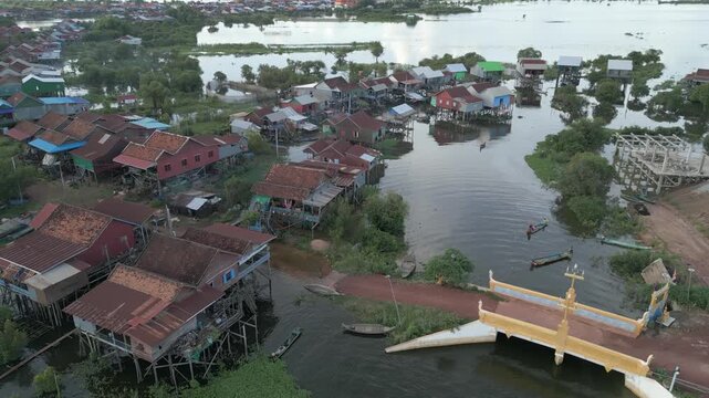 Aerial drone view showing traditional stilt houses, fishing boats, river canal, flooded land, and daily village life in Kompong Phluk near Tonle Sap Lake, Cambodia