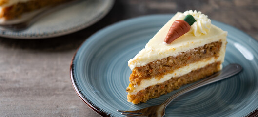 Carrot cake slice with cream cheese frosting on wooden table. Panoramic view