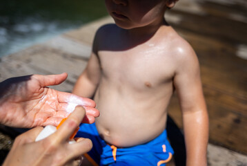 Mother applies sunscreen lotion to her child to protect the skin from UV rays