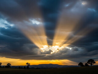 Sun rays shining through clouds in the sky at sunset