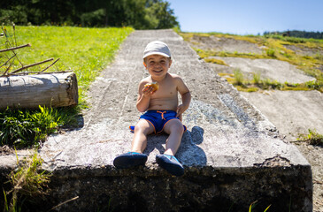 Child eats a sandwich while taking a break from play on a hot summer day