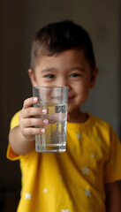 A young boy holding a glass of clear water with a smile : Photos for World Water Day promotion