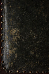 Textured leather surface with visible studded edge and aged finish. Bold contrast and rich tones...