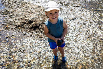 Child plays in a mountain stream on a hot summer day during vacation