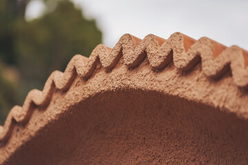 Close view of the edge of a clay roof showing its zigzag design. The structure is part of an old...
