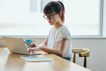Young Asian woman working remotely on a laptop at home