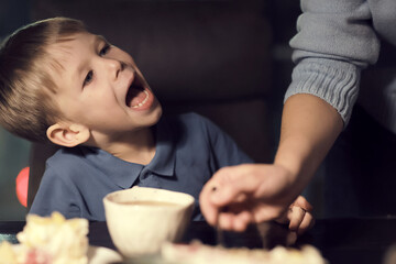 Mom and a 5-year-old boy light candles on a birthday cake, preparing for a birthday