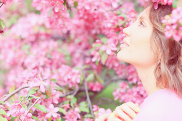 Fototapeta premium Springtime background, a woman in pink in a blooming cherry orchard, a model posing in a romantic style