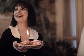 birthday cake with one candle, a girl makes a wish on her birthday