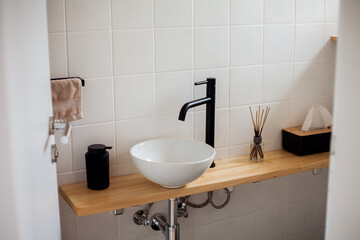 Minimalist bathroom. Black and white colors, wood. Aroma diffuser, towels. Home comfort. Interior.