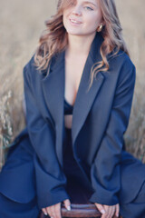 A female model poses sitting on a chair among nature and fields, an unusual photo of a summer Look