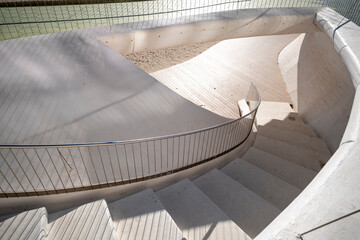 Modern architecture stairs with spiral curve and railing in concrete casting shadow for design focused abstract copy space background
