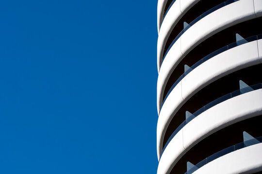 White modern architecture building curves with balcony lines in urban sky creating abstract minimalism and generous copy space background