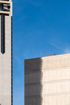 Modern urban architecture building facade in concrete with bold shadow and clean sky forming abstract geometry and copy space background