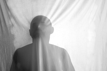 silhouette of a person against the background of a white sheet, the effect of a statue or a ghost