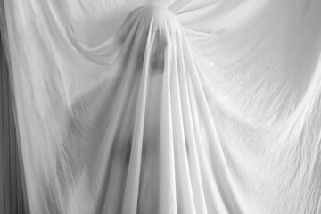 silhouette of a person against the background of a white sheet, the effect of a statue or a ghost