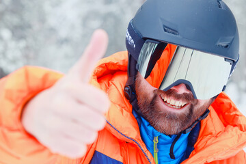 Man in ski helmet and glasses, snowfall extreme sports portrait close-up bearded cheerful