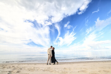 man and woman, couple in love on the seashore spring or autumn view seasonal photo in warm clothes
