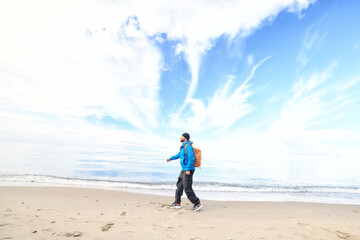 A guy with a backpack against the blue sky on the coast