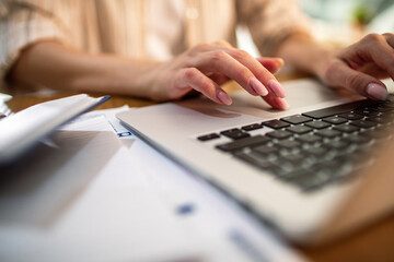 Woman typing on laptop at home office desk