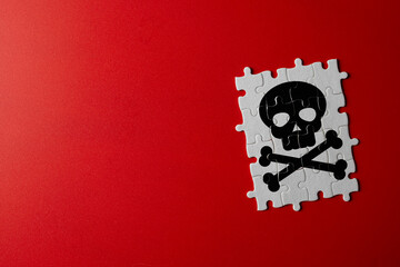 White jigsaw puzzle pieces assembled to form black skull and crossbones icon on red background....