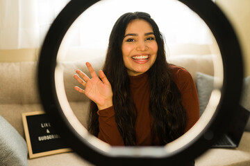 Influencer woman recording video for social media, smiling and waving at camera with ring light
