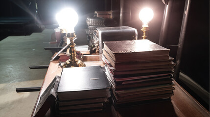 backstage. A table in the wings of a stage, stacked with bound scripts under dramatic lighting. event programs, museum guides, designed for cultural heritage projects and event programs.
