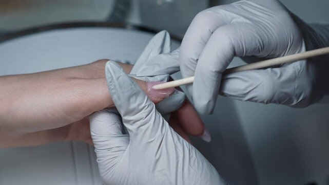 Creating nail shape with polygel on artificial nail manually using orange stick in manicure studio
