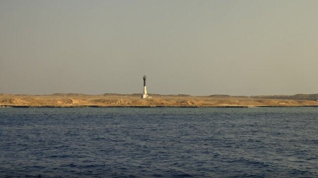 A wide-angle view from a vessel approaching Big Brother Island in the Red Sea. The island is characterized by its long, low-lying, and arid desert landscape.