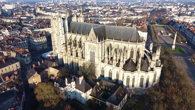 Aerial orbiting view of Saint Pierre and Saint Paul Cathedral in Nantes France, with its Gothic stone architecture dominating the historic cityscape, while Place Mar&eacute;chal Foch and the Louis XVI Column