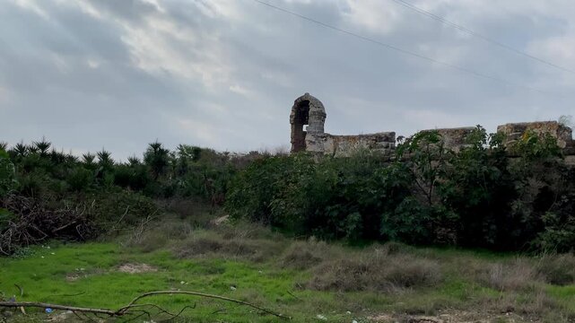 Stone castle in Sanlucar rises behind tall cypress trees, the Spanish flag flying above the fortified walls under a clear deep blue sky