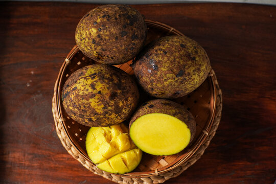 Citrus aurantifolia known as limus fruit in Sundanese culture. Traditional Indonesian citrus fruit with thick mottled skin and yellow flesh displayed in bamboo basket on wooden table.