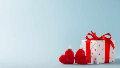 Gift, present box decorated with red ribbon bow and hearts, red heart shaped candles on light blue background. Valentine's day, 14 February, birthday, 8 march women's day gift. Love and romance.