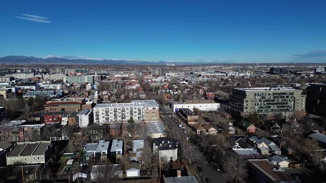 Residential and commercial zones extend east of Curtis Street with flat and pitched roofs in tight formation. Dense building textures, snow-capped peaks shape winter horizon, Denver, Colorado