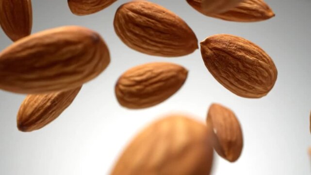 Scattered whole almonds suspended against a light background
