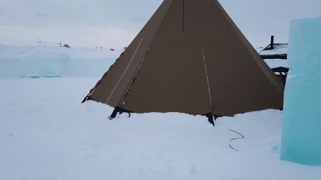 Traditional Sami Lavvu tent and ice blocks in a snowy arctic camp