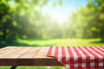Fototapeta premium Picnic table with checkered cloth looking out on a blurred green park background outdoor