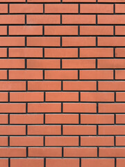 Fototapeta premium Orange brick wall texture with uniform color and dark mortar lines. Building material background for construction and architecture design.