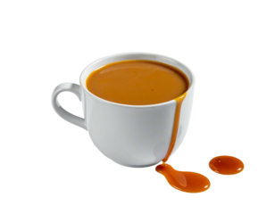 White mug overflows with rich, caramel-colored liquid, spilling onto surface