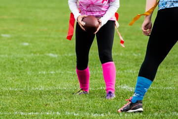 Confident female athlete dressed in pink uniform holding football during high school powder puff game with teenage girls.  © Jeanne Sager Photo