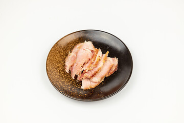 The cured pork in the round dish on the white background